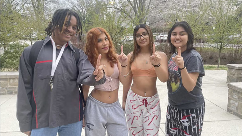 Four students holding one finger up for "First Gen" students