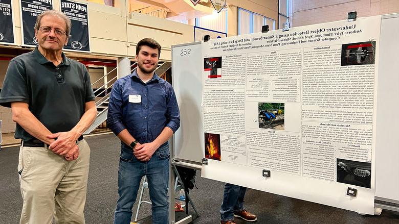 Student and professor stand next to research poster